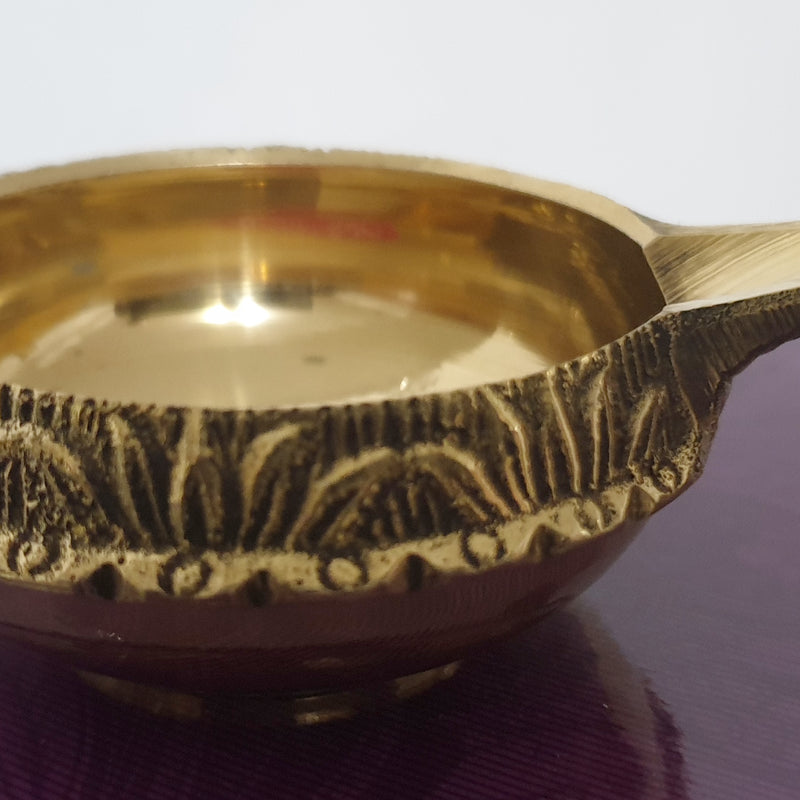 Agal Vilakku Brass Small, a gold-toned metal bowl with a glossy interior and a patterned outer band features one small protruding handle