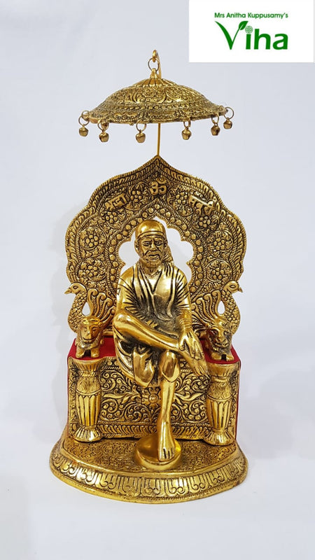 Sai Baba, seated figure on a throne beneath an arched backslab and a fringed hanging canopy