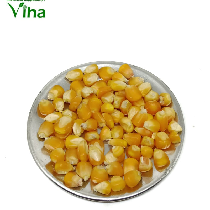 Sweet Corn Seeds (Solam Vidhaigal), a pile of glossy yellow corn kernels rests on a round silver-coloured plate against a plain white background