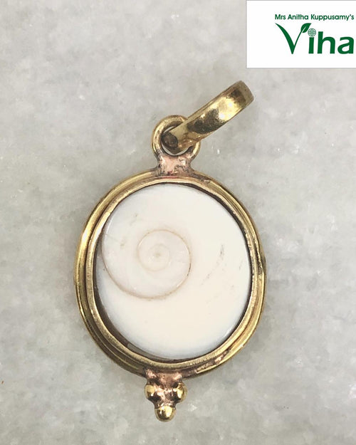 Gomathi Chakra Pendant with Brass frame, a shiny gold-toned pendant holding a round white shell piece with one brown spiral