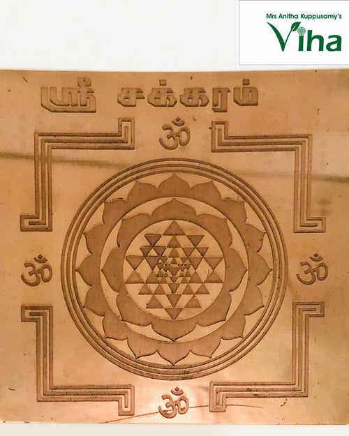 Sri Chakra Yantram, a square, copper-colored metallic plate with an etched central lotus and geometric pattern, surrounded by four symbols and Tamil script