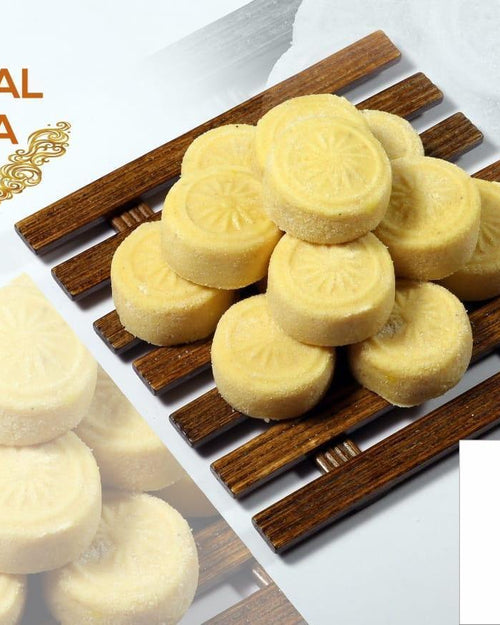 Special Peda, a product photograph showing ten yellow round patterned sweets on a dark wooden slatted rack beside paler ones