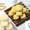 Special Peda, a product photograph showing ten yellow round patterned sweets on a dark wooden slatted rack beside paler ones
