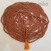 5 Face Rudraksh Japa Mala, a coiled loop of rough brown beads ending in an orange tassel