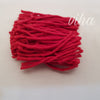 A folded bundle of red cotton lamp wick strands on a pale surface