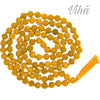 Haldi Mala / Turmeric Mala, a long strand of matte yellow beads, threaded and knotted together with orange string, terminating in an orange tassel
