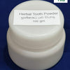 Herbal Tooth Powder, a small opaque white plastic round jar with a label on top, set against a dark blue background