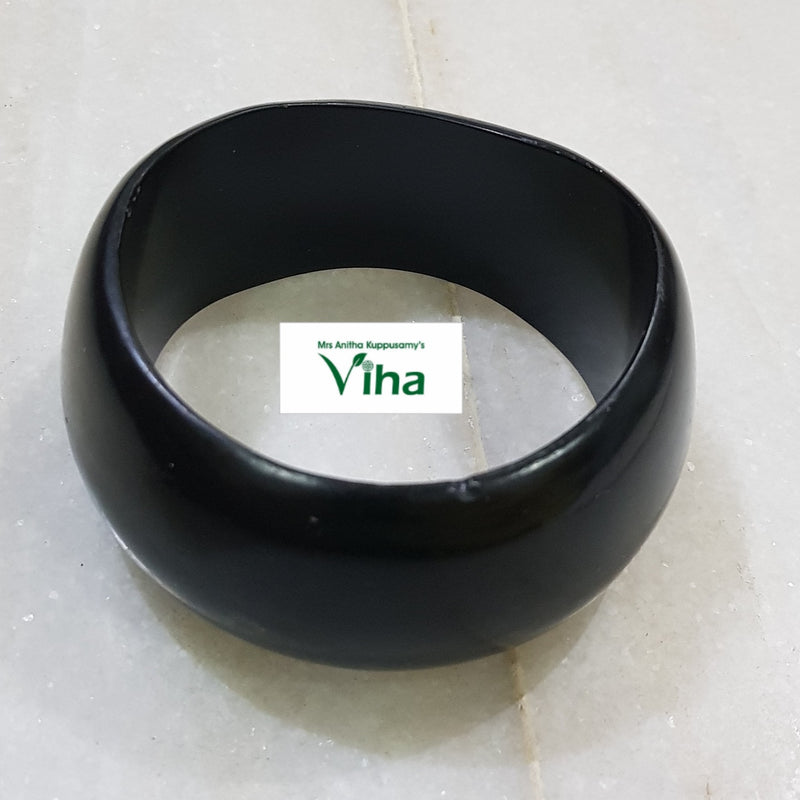 Karungali Wood Bangle, a thick black matte bangle with a slightly irregular rounded shape resting on a tiled surface