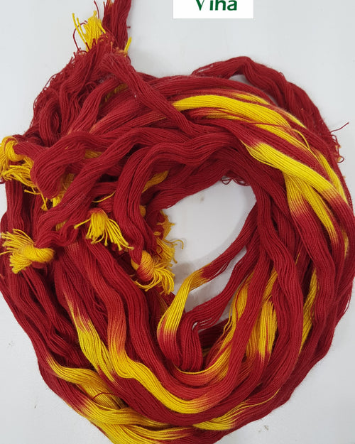 A coiled length of twisted red and yellow cotton sacred thread