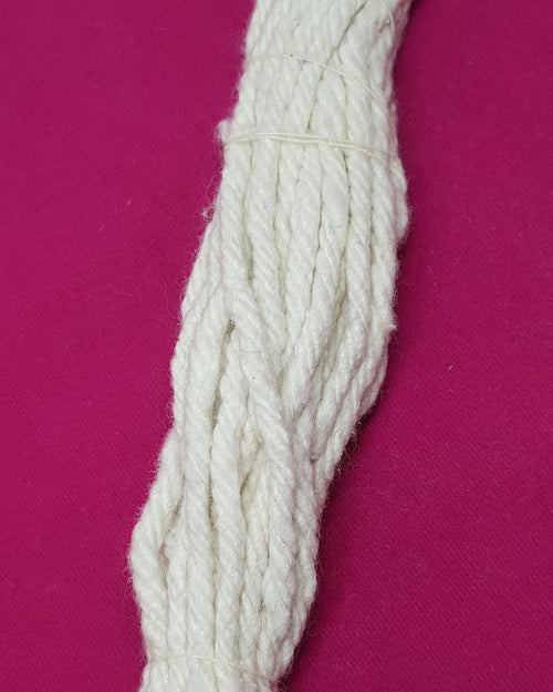 A single long twisted white cotton wick strand on a magenta cloth