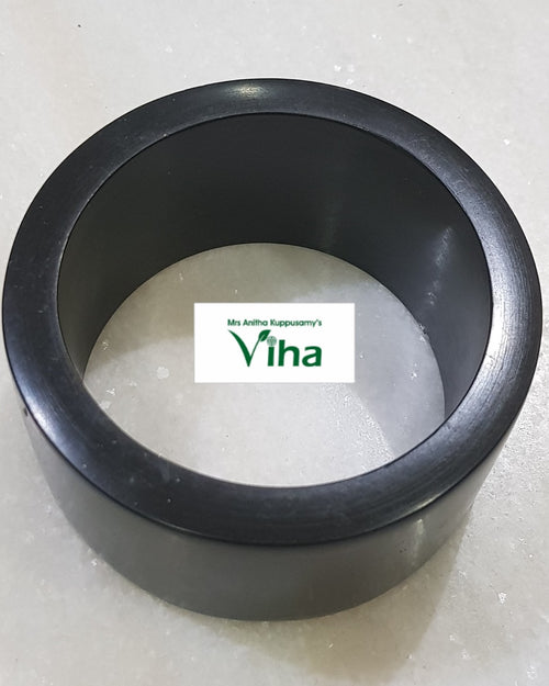 Karungali Wood Bangle, a wide black ring with a smooth finish resting on a speckled white surface