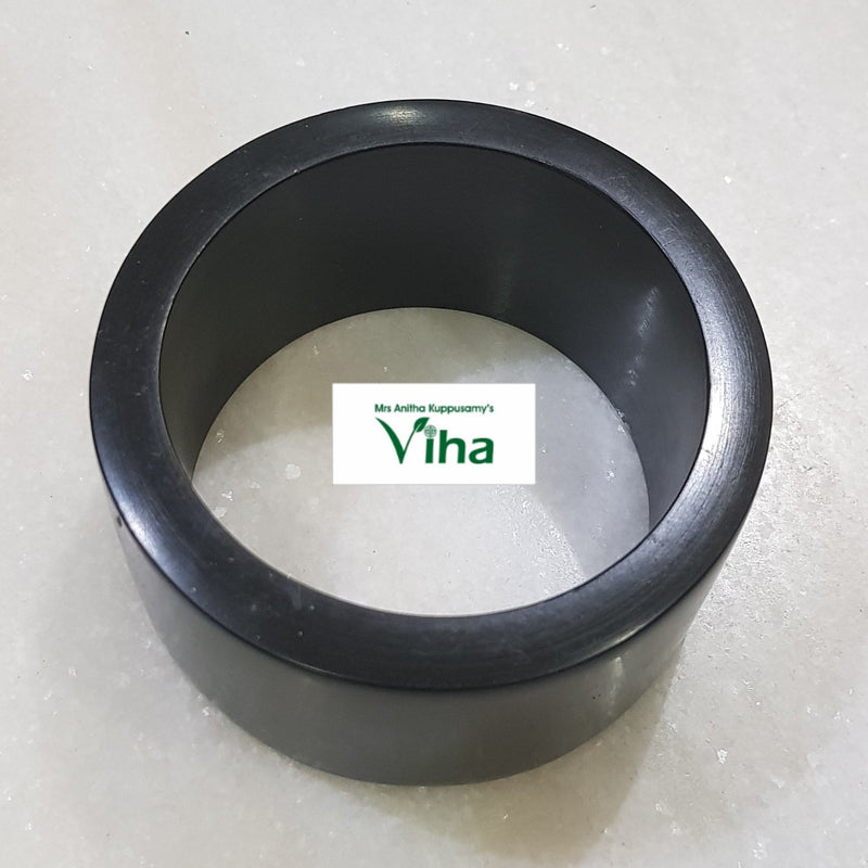 Karungali Wood Bangle, a wide black ring with a smooth finish resting on a speckled white surface