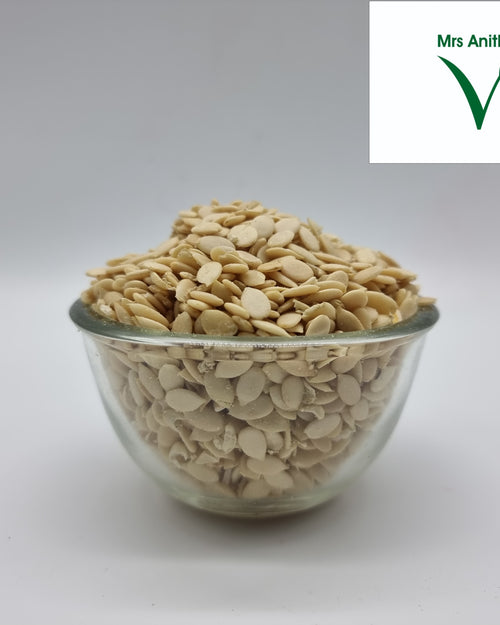 Water Melon Seeds Skin Removed Edible, a small clear glass bowl filled with numerous beige, flat, oval seeds against a plain background