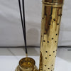 Agarbathi Stand (Brass), a gold-toned metal round container with star cutouts, standing beside its stepped base holding two black sticks