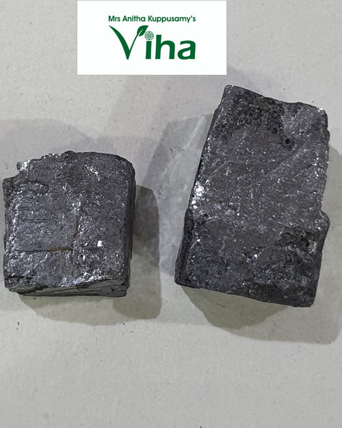 Anjanakkal (surma stone), two dark grey irregular stones with a metallic sheen, side by side on a light surface