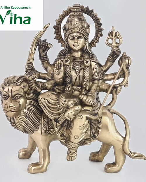 Durga Devi in brass, many-armed figure with a rayed halo seated on a striding lion with a full mane