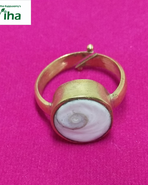Gomathi Chakra Brass Ring - Men, a gold-toned adjustable ring featuring a round setting with a white swirl-patterned inlay centered on a pink surface