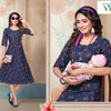Feeding Kurti Full Stitched, a woman in a blue patterned dress with half sleeves, purple headband, and long pink beaded necklace holds a doll