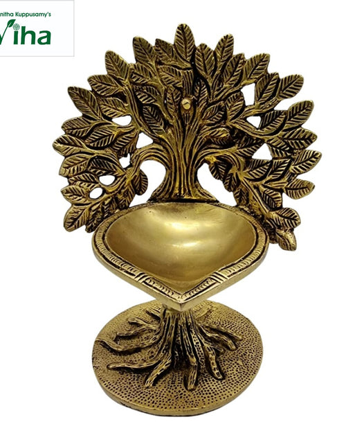 Kalpavriksha brass lamp, leafy wish-tree rising behind a leaf-shaped oil bowl with exposed roots
