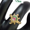 Impon Ring, a gold-toned ring featuring a turtle-shaped face embedded with green, red, and clear stones displayed on a black hand model