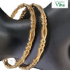 Impon Bangles, two gold-toned textured metal bangles with intricate cutout patterns on a dark display stand