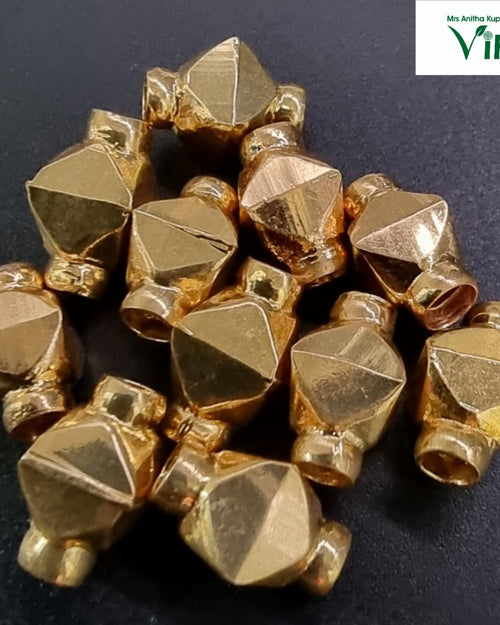 Impon Thali Kundu beads in gold-tone metal, faceted and piled on a dark background