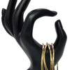 Impon Bangles, four gold-toned bangles hang from the thumb of a black hand-shaped mannequin stand against a plain white background