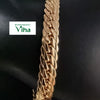 Impon Bracelet, a shiny gold-toned flat curb chain with interlocking links against a dark background