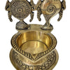 Sangu Chakra Lamp Brass, a gold-toned metallic vessel with an etched base and two standing objects featuring intricate patterns behind its bowl