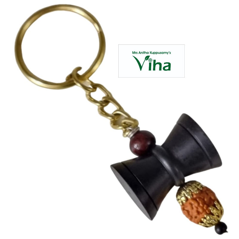 Ebony Wood Damru Rudraksh Key Chain, a gold-toned ring with a four-link chain, a reddish bead, a black hourglass shape, and a textured bead