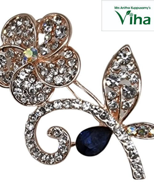 Gold-toned floral saree pin with a dark blue teardrop decoration