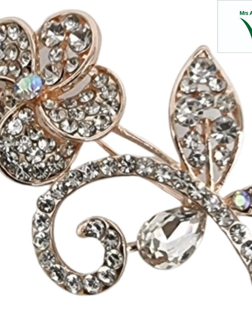 Saree Pin, a gold-toned metal brooch features a five-petaled flower, a curved stem inset with clear stones, two teardrop leaves, and three iridescent stones
