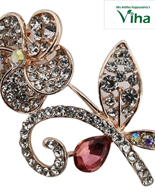 Saree Pin, a gold-toned flower-shaped brooch with five petals paved in clear stones, a central iridescent stone, a stem, leaves and a pink teardrop stone