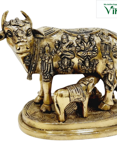 Kamadhenu cow and calf in brass, cow with rows of small deity figures across the flank and a calf beneath, on an oval base