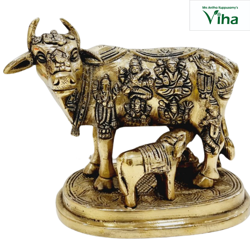 Kamadhenu cow and calf in brass, cow with rows of small deity figures across the flank and a calf beneath, on an oval base