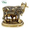 Kamadhenu Cow And Calf - Big, a gold-toned metallic cow figurine featuring embossed human figures on its body and standing on an oval base