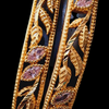 Impon Bangles, two textured, gold-toned openwork bangles featuring leaf designs, beaded borders, and inset marquise pink stones
