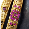 Impon Bangles, two gold-toned textured bangles adorned with embedded red stones in floral and abstract patterns