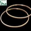 Impon Baby Bangles, two gold-toned metal bangles with textured crosshatch patterns and smooth inner bands against a black background