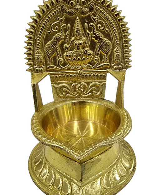 Gaja Lakshmi Vilakku - Brass, a gold-toned metallic oil lamp features an ornate arched backplate depicting seated figures and elephants above a bowl with base
