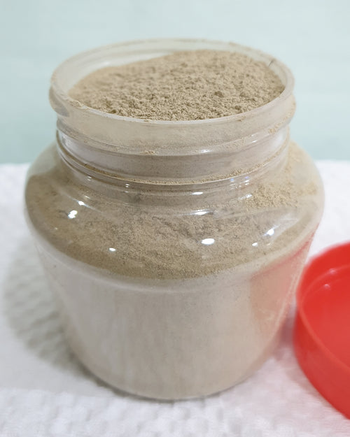 Pimple Face Pack, a transparent plastic jar with threaded neck contains beige powder, beside a red circular lid on a white surface
