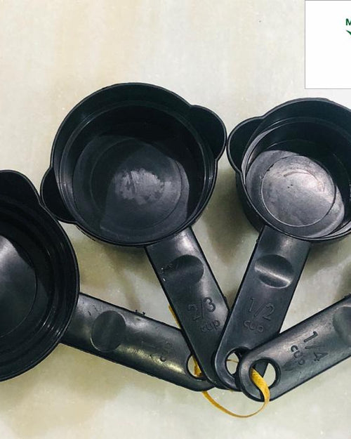 Measuring Cups, four black measuring cups with handles, each showing capacity markings and joined by a thin yellow string