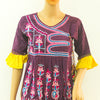 Traditional Kath-Putli Kedia and Tulip Pants, a dark purple tunic with pink embroidery, yellow ruffled cuffs, and pom-pom hem on a mannequin