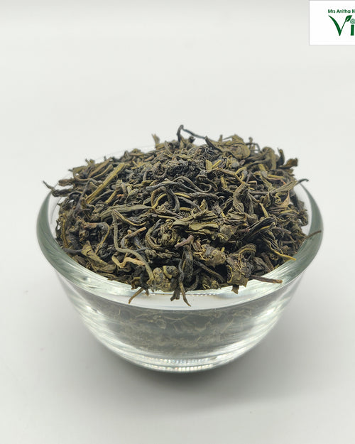 Ooty Green Tea - Long Leaf in a clear glass bowl filled with dried dark leaves
