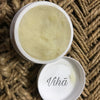 Shea Butter, an open circular white jar filled with pale yellow solid on a woven brown rope background with one detached white lid beside it