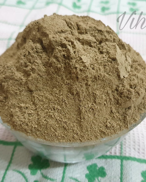 Adult Herbal Bath Powder, a small glass bowl filled with mounded brown powder sits on a white fabric patterned with green floral motifs
