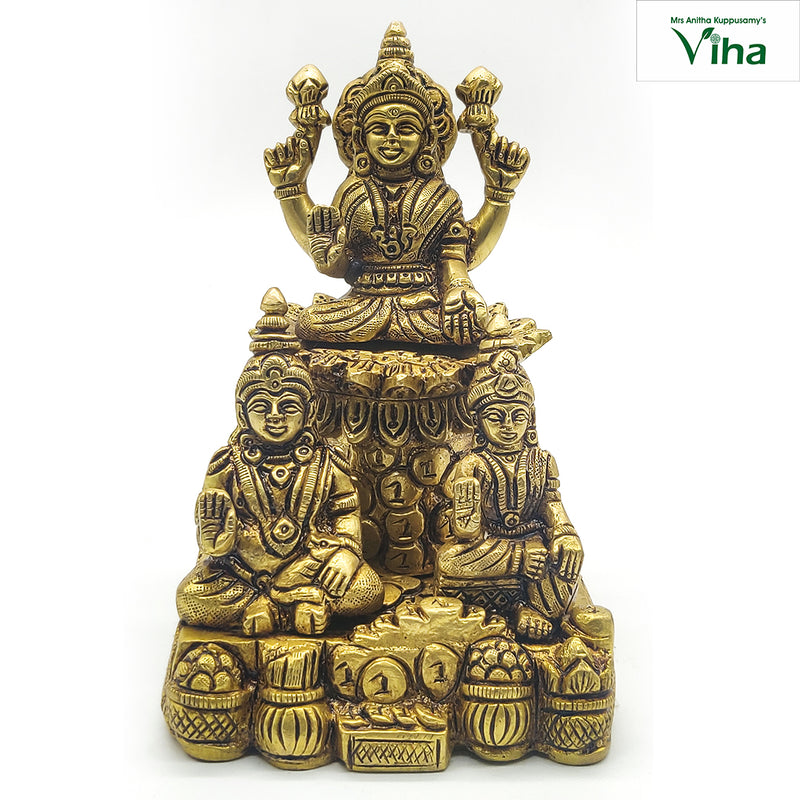 Kuberar in brass, a standing figure above two seated figures, with pots and coin heaps across the base