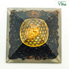 Black Tourmaline Pyramid for Vastu, a square pyramid filled with black pieces, copper-toned chips, a gold-toned flower-of-life disc, and spiral