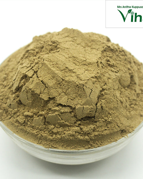 Triphala Powder, a translucent glass bowl containing a rounded mound of fine, matte, brownish-grey powder with surface cracks