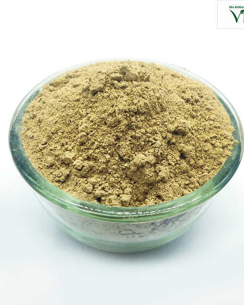 Tulsi Powder, a transparent glass bowl filled with brownish-yellow powder mound against a white background